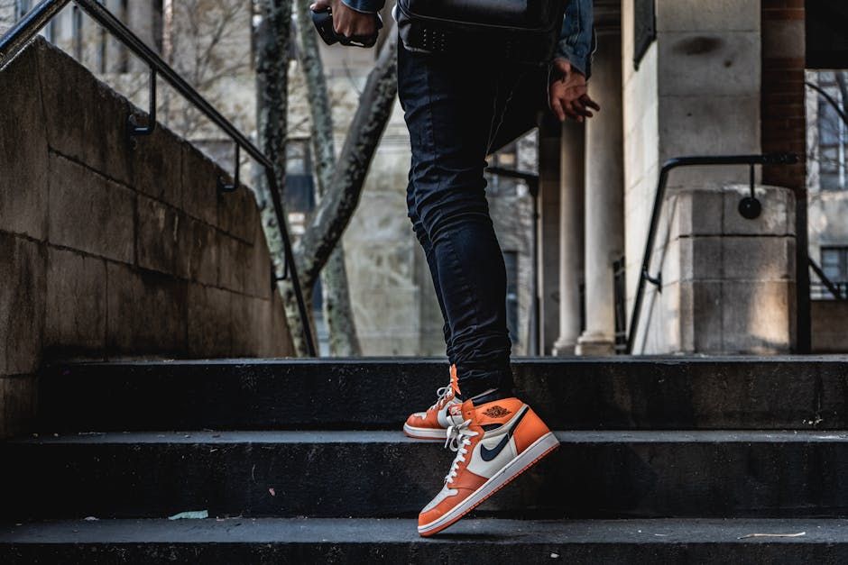 A person climbing outdoor stairs wearing stylish orange and white sneakers in an urban setting.