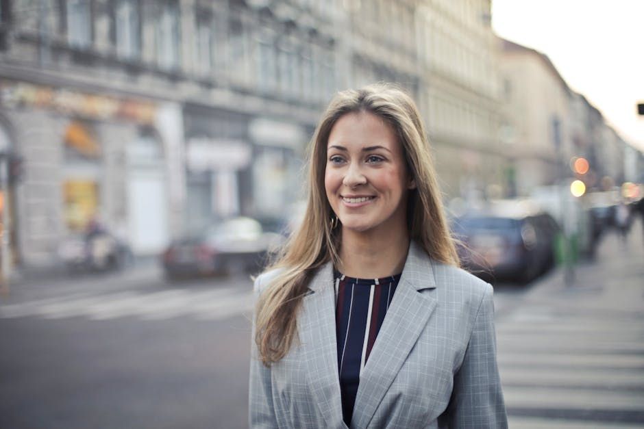 Confident businesswoman smiling outdoors in urban Budapest setting.