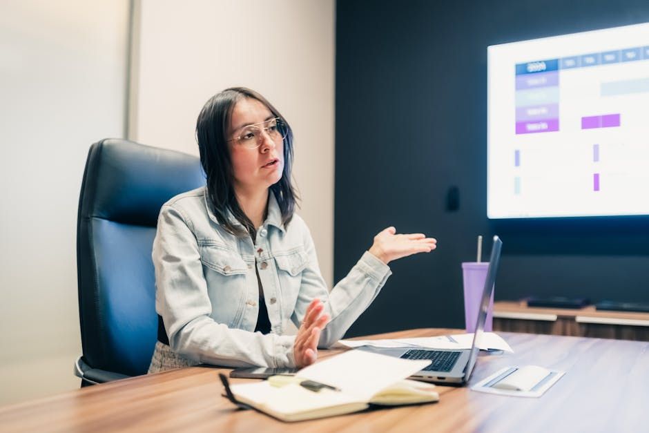 Businesswoman explaining a concept during a meeting with a presentation displayed on screen.