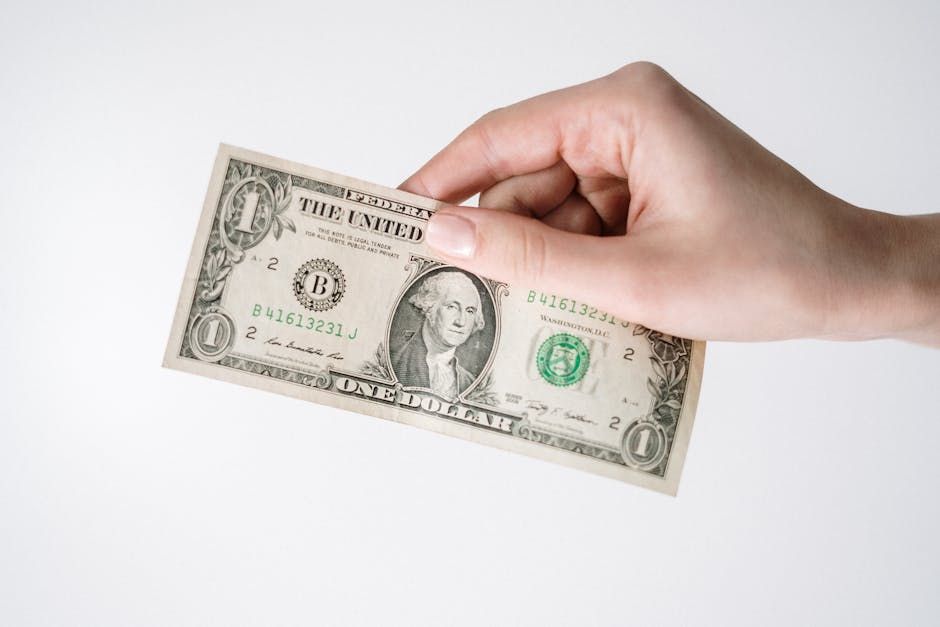 Close-up of a Caucasian hand holding a US one dollar bill against a white background.
