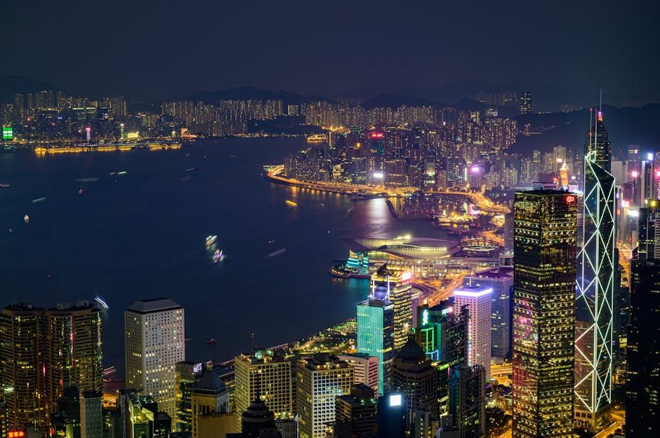 Stunning nighttime view of Hong Kong Island with illuminated skyscrapers and vibrant cityscape across Victoria Harbor.